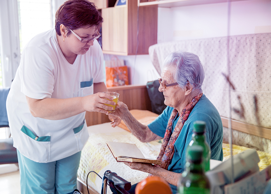 Eine Pflegerin kümmert sich um eine alte Dame. #Gib8aufGrippeschutz.