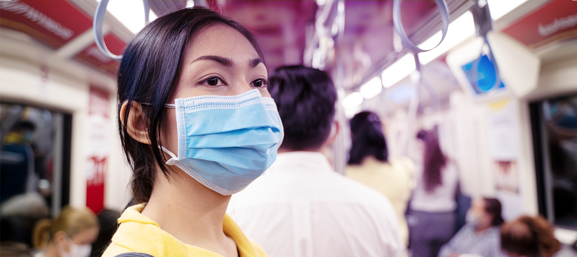 Frau mit medizinischer Maske im stark frequentierten öffentlichen Verkehrsmittel