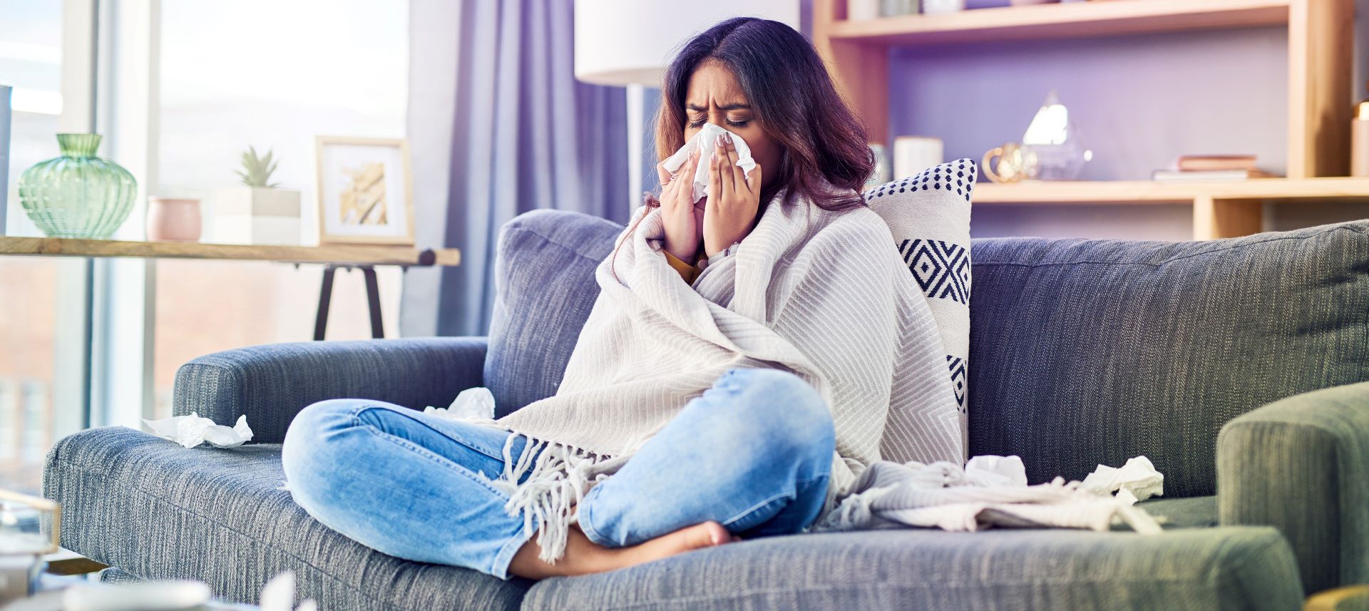 Frau sitzt auf dem Sofa und hat sich mit Grippe infiziert.