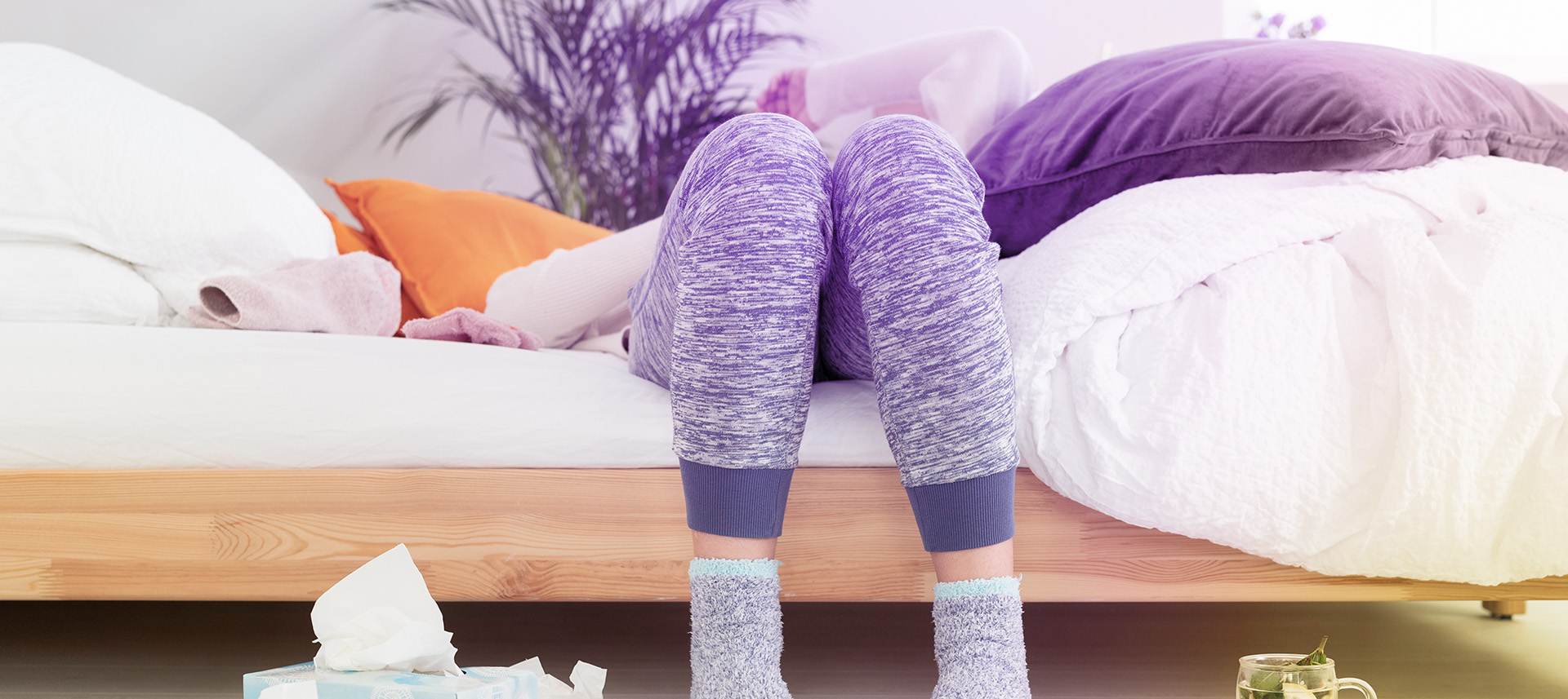 Frau hat sich mit Grippe infiziert und liegt erschöpft im Bett.